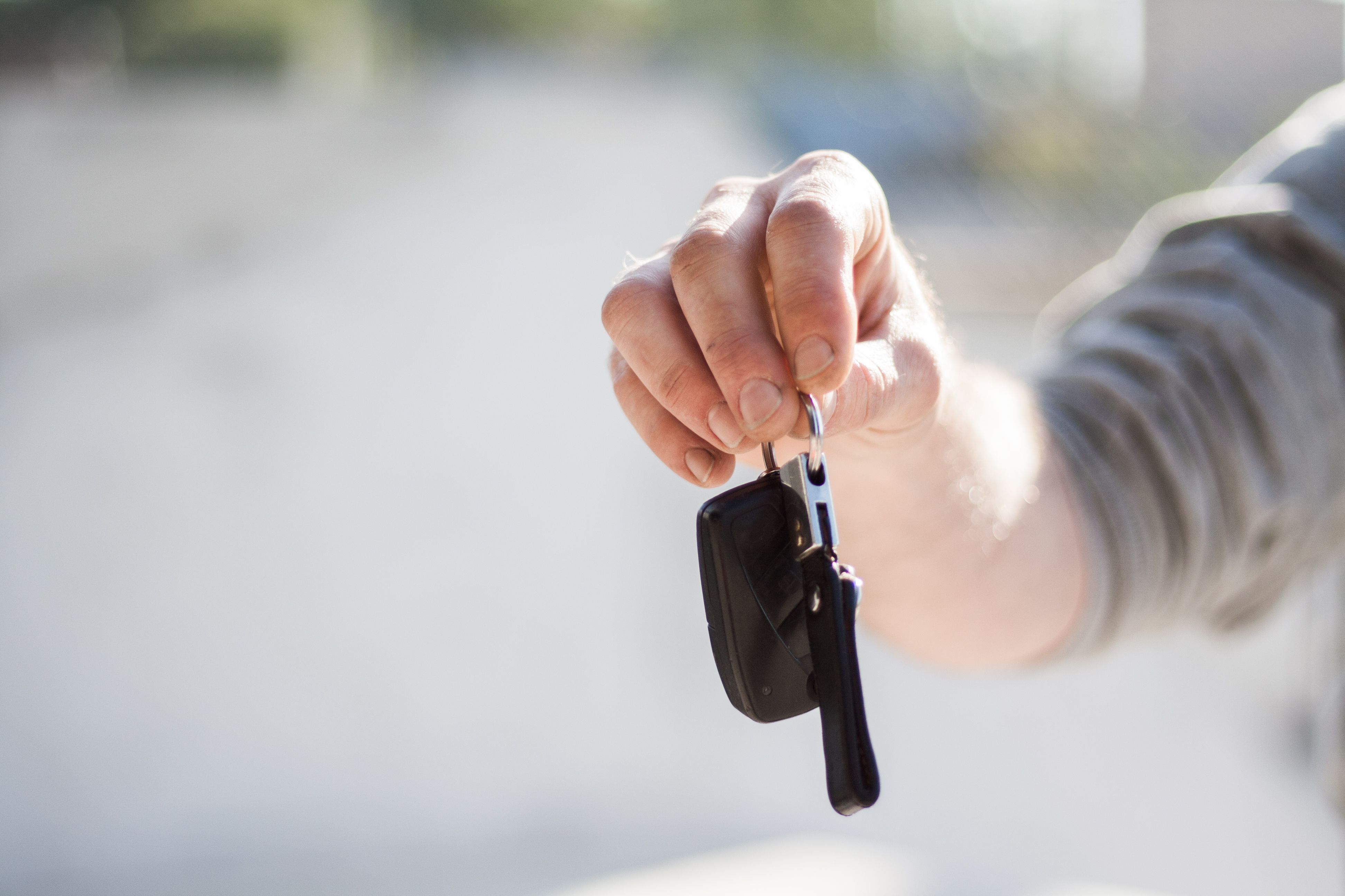 Mão entregando a chave de um carro — momento de decisão entre alugar ou financiar