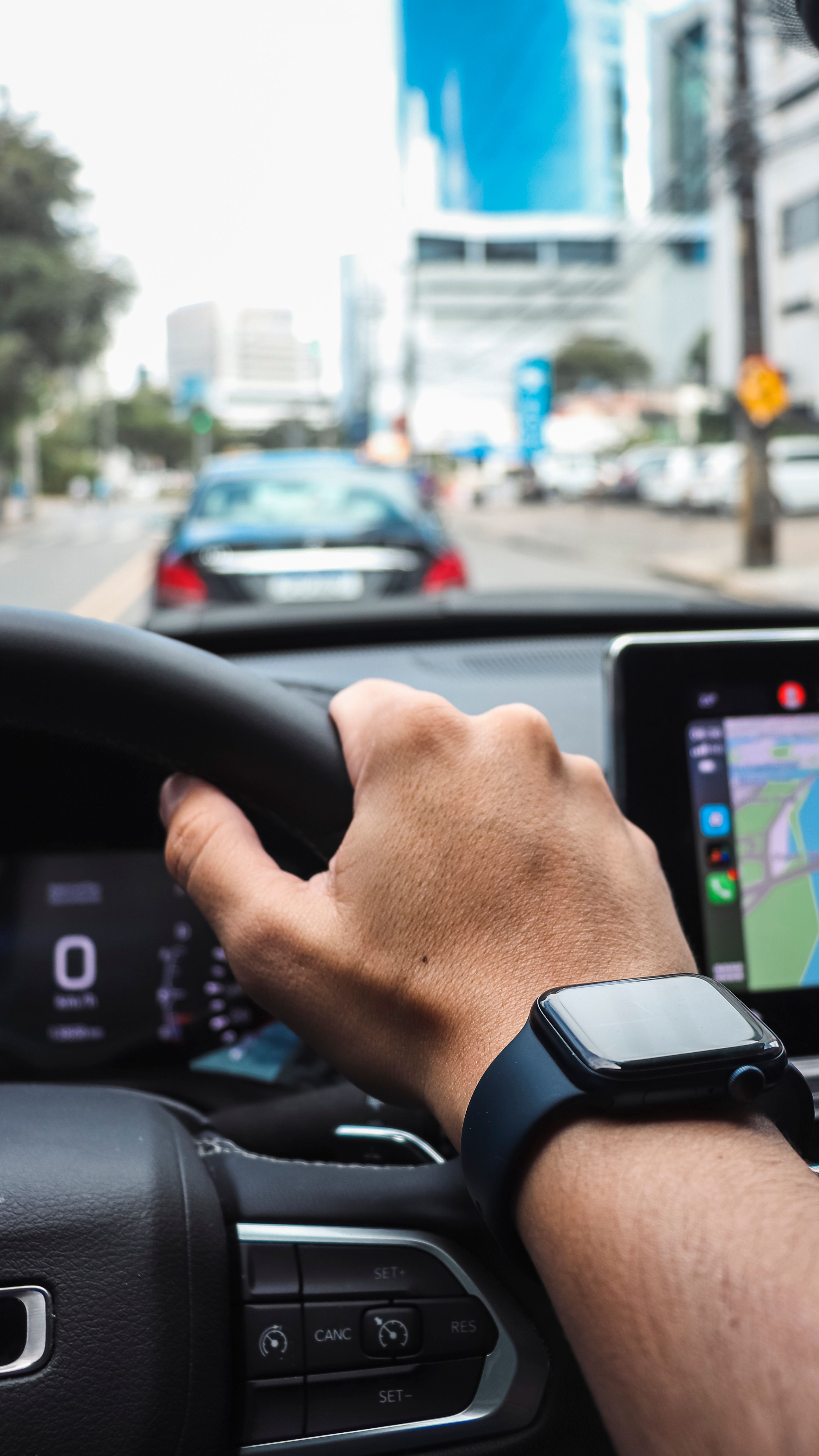 Motorista de aplicativo dirigindo na cidade, com GPS ligado no painel